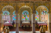 Dining hall with hand painted arches and stained glass windows, tables laid for a meal