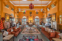 Drawing room hung with family portraits and trophies, twin marble fireplaces and a red chandelier