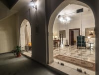 Arched corridor at night looking through to a lounge lit by a chandelier