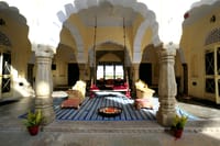 Open pillared hall of scalloped arches with a hanging swing seat and floor cushions