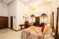 High ceilinged suite with a green glass chandelier, painted cupboard doors and arched windows