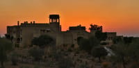 Fort silhouetted against a desert sunset