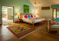 Cottage bedroom with a wooden floor, kilim rugs and doors open to the garden