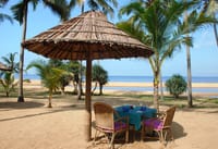 Table for two under a thatched parasol on the beach