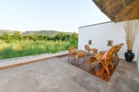 Walled veranda with cane chairs facing grassland
