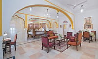 Suite sitting room with a yellow scalloped arch and a canopy bed in the room beyond