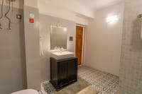Guest bathroom with patterned tiled floor, walk-in shower and dark wood vanity