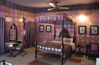 Four poster bed in purple papered room