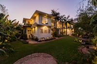 Villa lit at dusk above the lawn