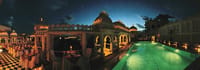 Rooftop Baori Pool at night flanked by white pillared pavilions and dining tables