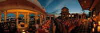 Candle-lit dinner tables on the rooftop terrace at dusk under domes and chhatris