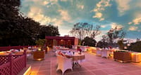 Terrace dining under a sunset sky with white-clothed tables and lanterns