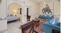 Suite interior with hand-painted elephant fresco, arched alcove bed and jhoola swing seat