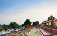Riverside dining terrace with red umbrellas over chequered paving