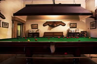 Billiards table under a shaded lamp