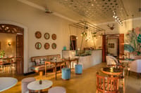 Cafe interior with cane seating, marble counter and jaali-panelled ceiling at Amrapali House of Grace, Goa