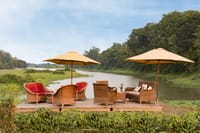 Wicker chairs and umbrellas on the riverside deck above the Diphlu river
