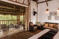 A cottage verandah with cane chairs looking into the trees