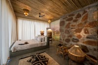 Bedroom with exposed stone wall and bamboo ceiling