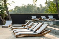 Teak loungers beside the black edged swimming pool