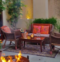 Cane armchairs around a fire in a courtyard corner at dusk
