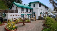 Green-roofed manor buildings around a flowering garden