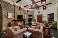Lounge with fireplace, armchairs and bookshelves