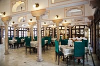 Restaurant interior with green chairs under historic arches
