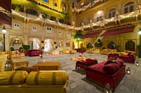 Painted durbar hall with red divans lit at night