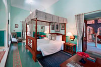 Canopy bed and rugs in green-floored room