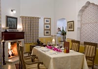 Dining table laid beside a lit fireplace