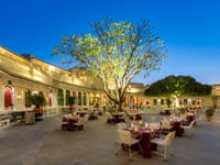 Courtyard laid for dinner around a lit tree