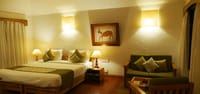 Cottage bedroom with green settee and framed painting