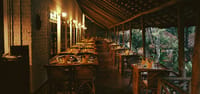 Restaurant verandah tables laid under a thatched roof