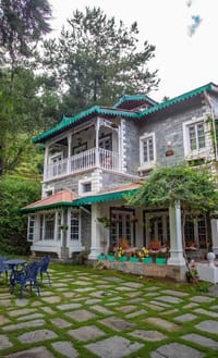 The villa from the garden path with blue chairs on the grass