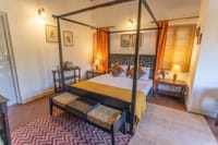 Magpie room with dark four poster bed and gold curtains