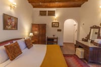 Rosefinch room with wood frame bed and archway to the hall