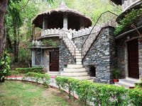 Round stone cottage with thatched roof and external stair