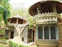 Two stone pavilions with conical thatch and lattice windows