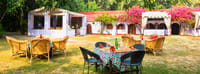Garden dining tables and wicker chairs on the lawn outside the lodge