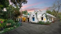 The white 1937 bungalow at dusk, with its garden, herb beds and blue shutters, Lutyens Bungalow, New Delhi
