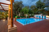 The swimming pool in the garden at dusk, seen from the carved-pillar veranda, Lutyens Bungalow, New Delhi