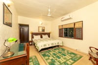 A large twin room with a writing desk, green kilims and a garden window, Lutyens Bungalow, New Delhi