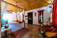 A cottage bedroom with a four-poster bed under a bamboo ceiling