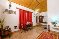 A cottage bedroom with red curtains and a table by the window
