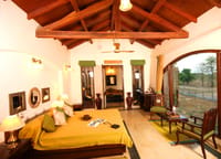 A bedroom under a timber roof, the meadow beyond
