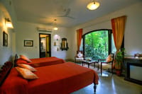 A bedroom with red covers and the forest outside