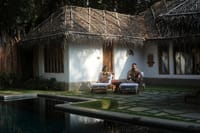 The pool deck, thatched villas reflected in the water