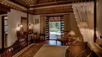 A heritage-style pool villa bedroom with a canopy bed