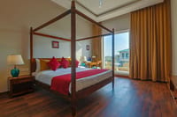 A four-poster bed and wooden floor in a room at Ananyamaya